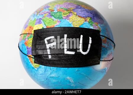 Globe with a political map of the world with a black medical mask and the inscription `FLU` Stock Photo